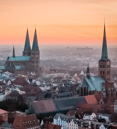 Türme von St. Marien und Jakobi im Morgendunst über der Stadt Lübeck